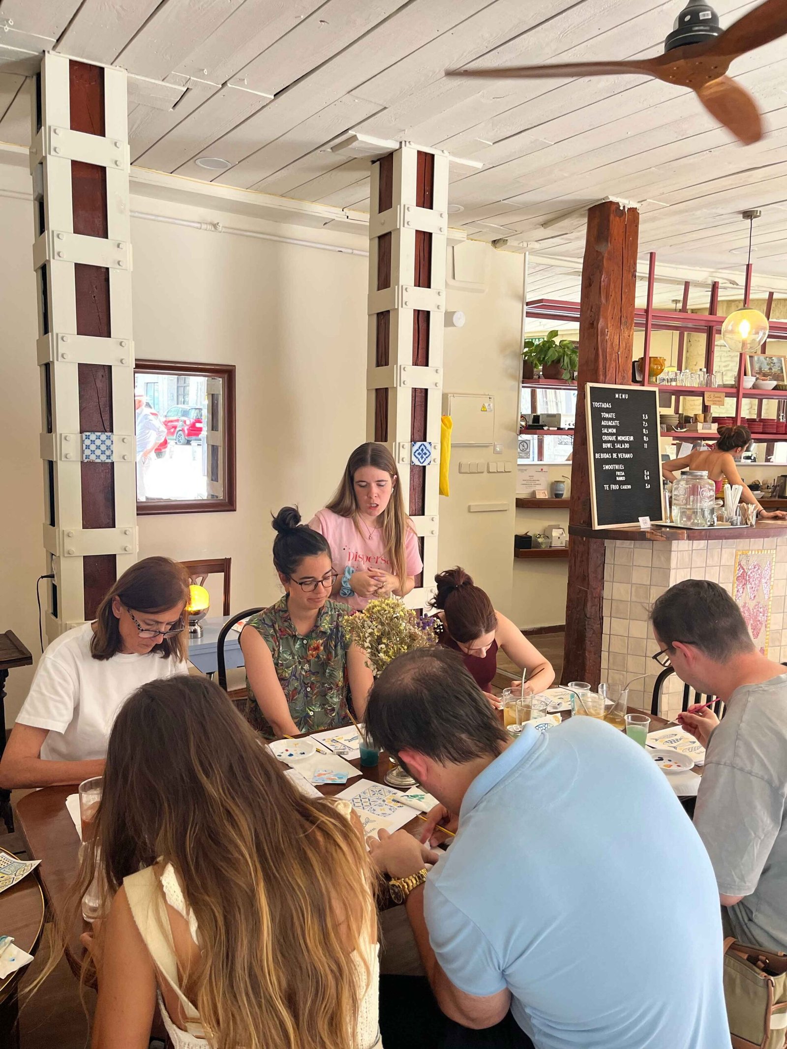 Taller de acuarela en Mosaik Cafe Madrid personas pintando y Ana explicando